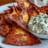 Golden-baked pita chips paired with tangy tzatziki sauce for a light, vegetarian appetizer.