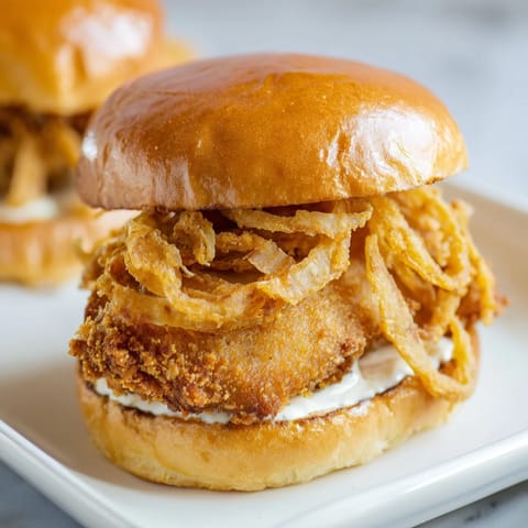 Juicy buttermilk-marinated chicken topped with creamy garlic aioli and crispy fried onions on a soft brioche bun.