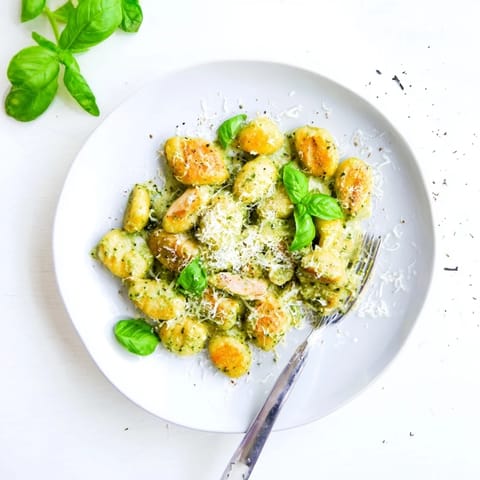 Perfectly cooked gnocchi and tender chicken bites swimming in rich pesto cream, garnished with fresh basil and Parmesan for a weeknight meal.