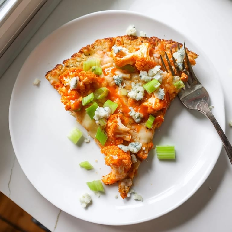 Golden-brown Buffalo Cauliflower Pizza topped with crumbled blue cheese, celery, and parsley, ready to serve for a vegetarian dinner.