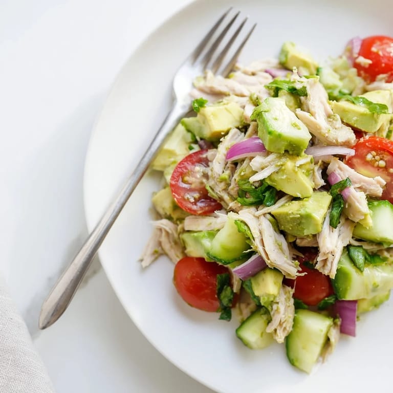 Healthy avocado chicken salad served in lettuce cups, ready for a low-carb lunch, with vibrant green avocado and red tomatoes.