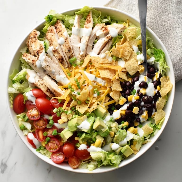 A close-up of Crunchy Taco Chicken Salad topped with creamy avocado and melted cheddar cheese.  