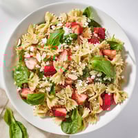 Bright, fresh Spring Spinach Strawberry Pasta Salad with tender bow-tie pasta, baby spinach, and sliced strawberries glistening with poppy seed dressing.