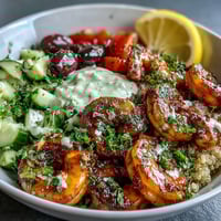 A vibrant Mediterranean Shrimp Bowl showcases plump seared shrimp, colorful veggies, and a creamy tahini drizzle over fluffy quinoa.